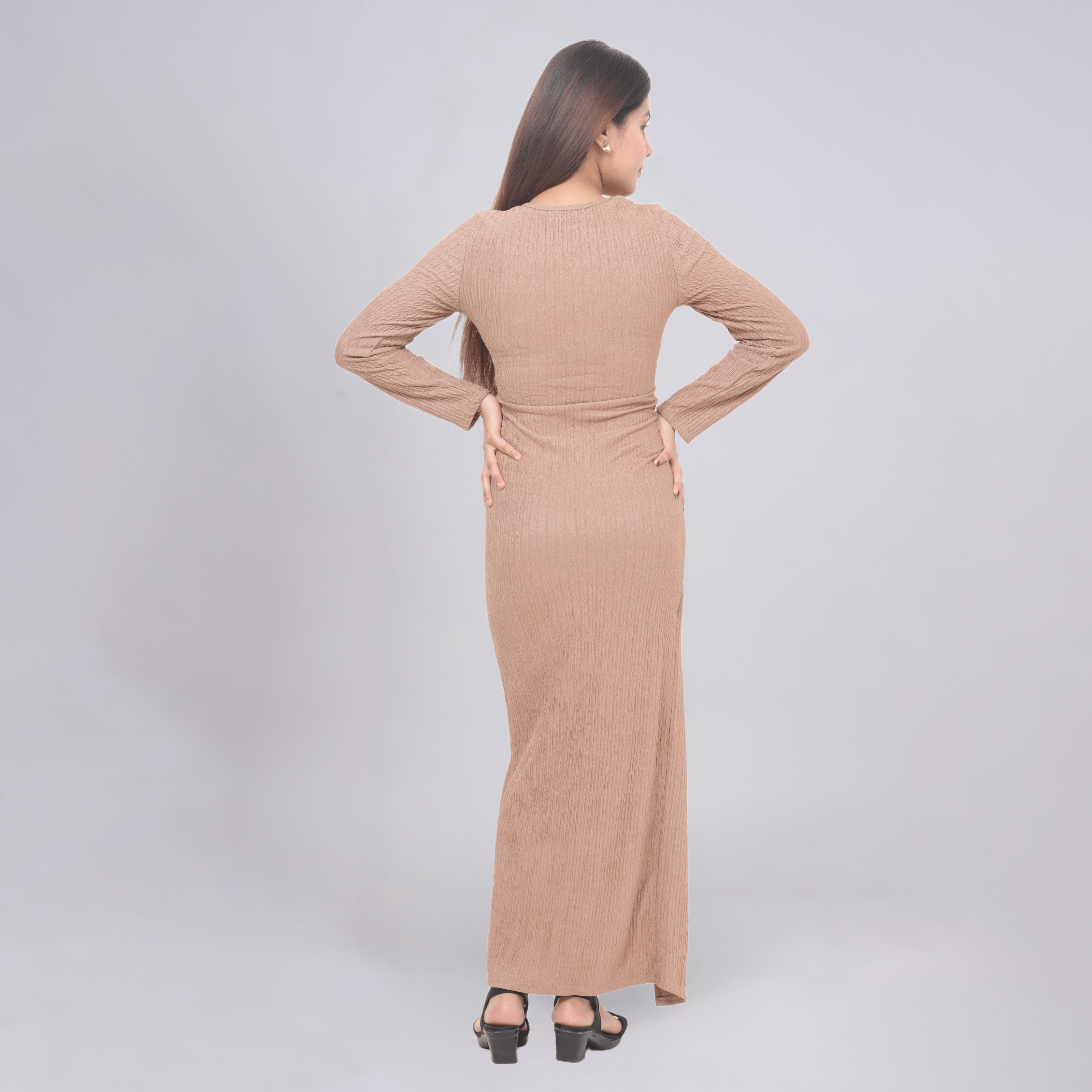 Woman wearing a beige long dress against a light gray background