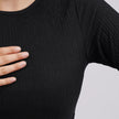 Person wearing a black textured shirt with a neutral background